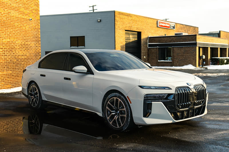 White BMW 7 Series sedan in front of a brick building