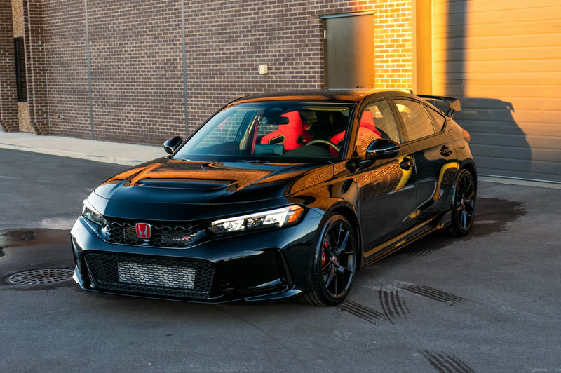 Black Honda Civic Type R in front of a brick wall in low sun