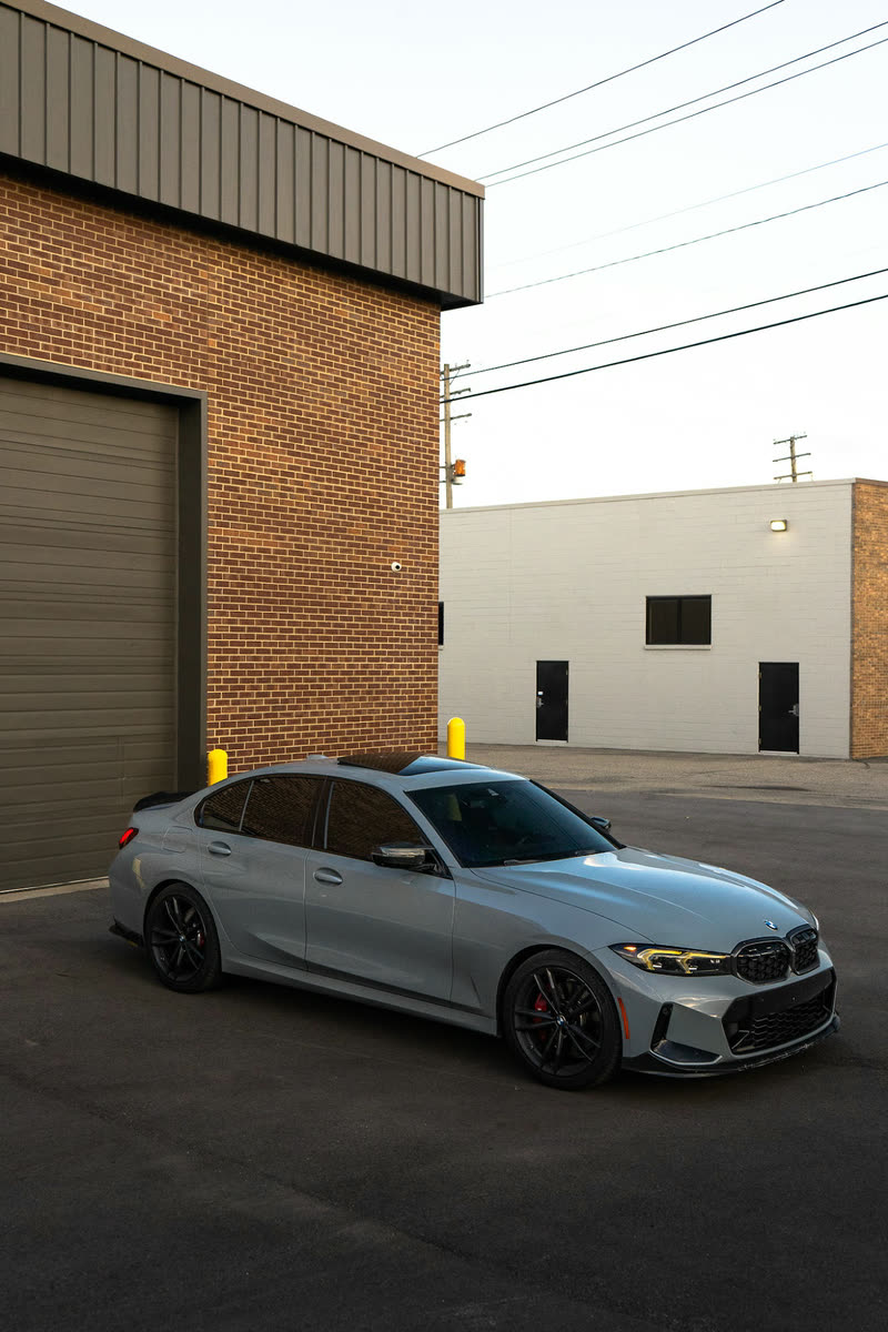 Grey BMW M340i sedan in front of a brick building
