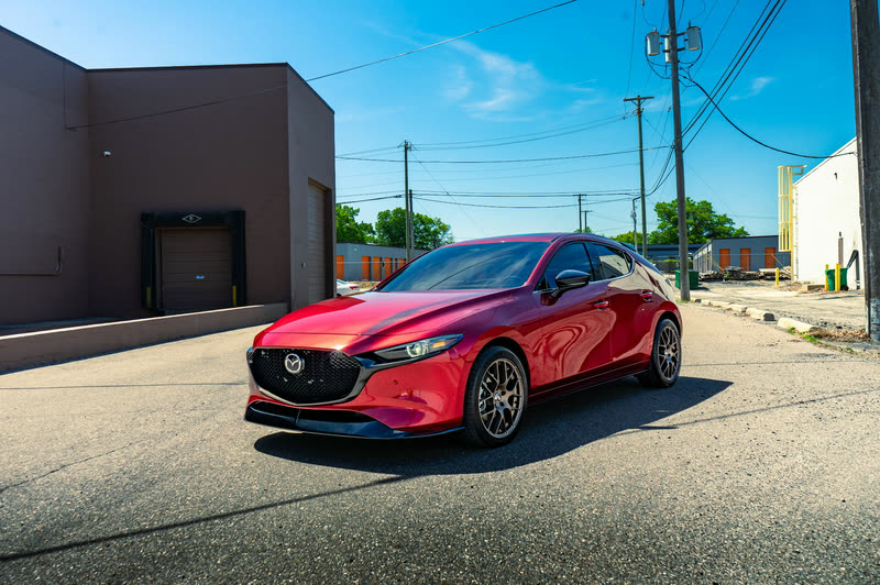 Red Mazda3 hatchback parked on an asphalt lot