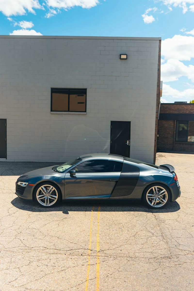 Dark grey Audi R8 in side profile in a parking lot